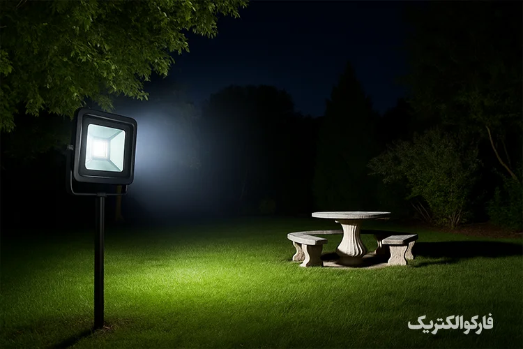 پروژکتور LED نصب‌شده در یک محوطه بیرونی که فضای باغ یا حیاط را در شب با نور سفید روشن کرده است